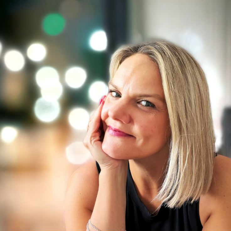 Abby with blonde hair and a black top against a blurred bokeh background