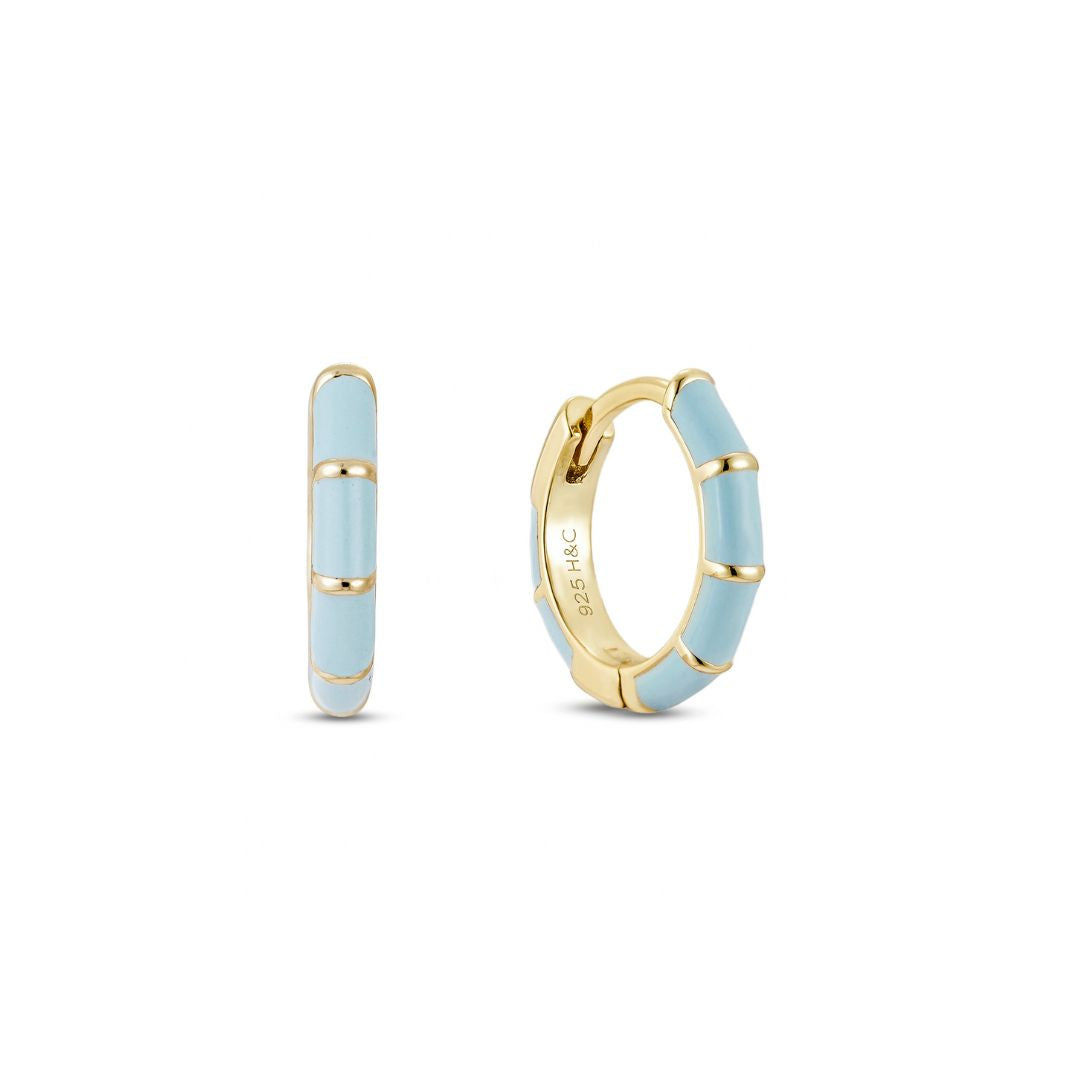 A pair of gold-plated huggie hoop earrings with blue enamel inlay, displayed against a white background.