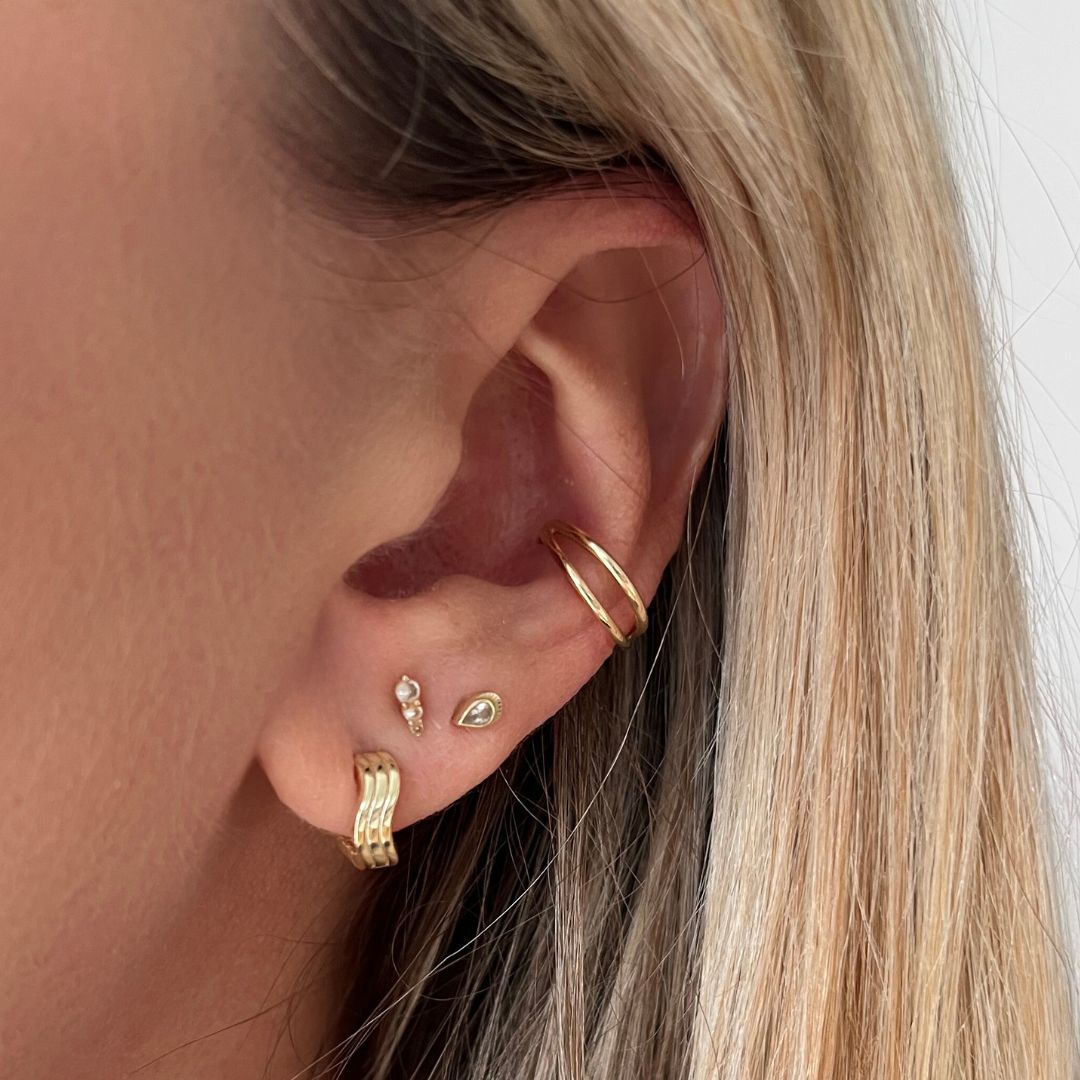 Close-up of an ear wearing gold earrings 