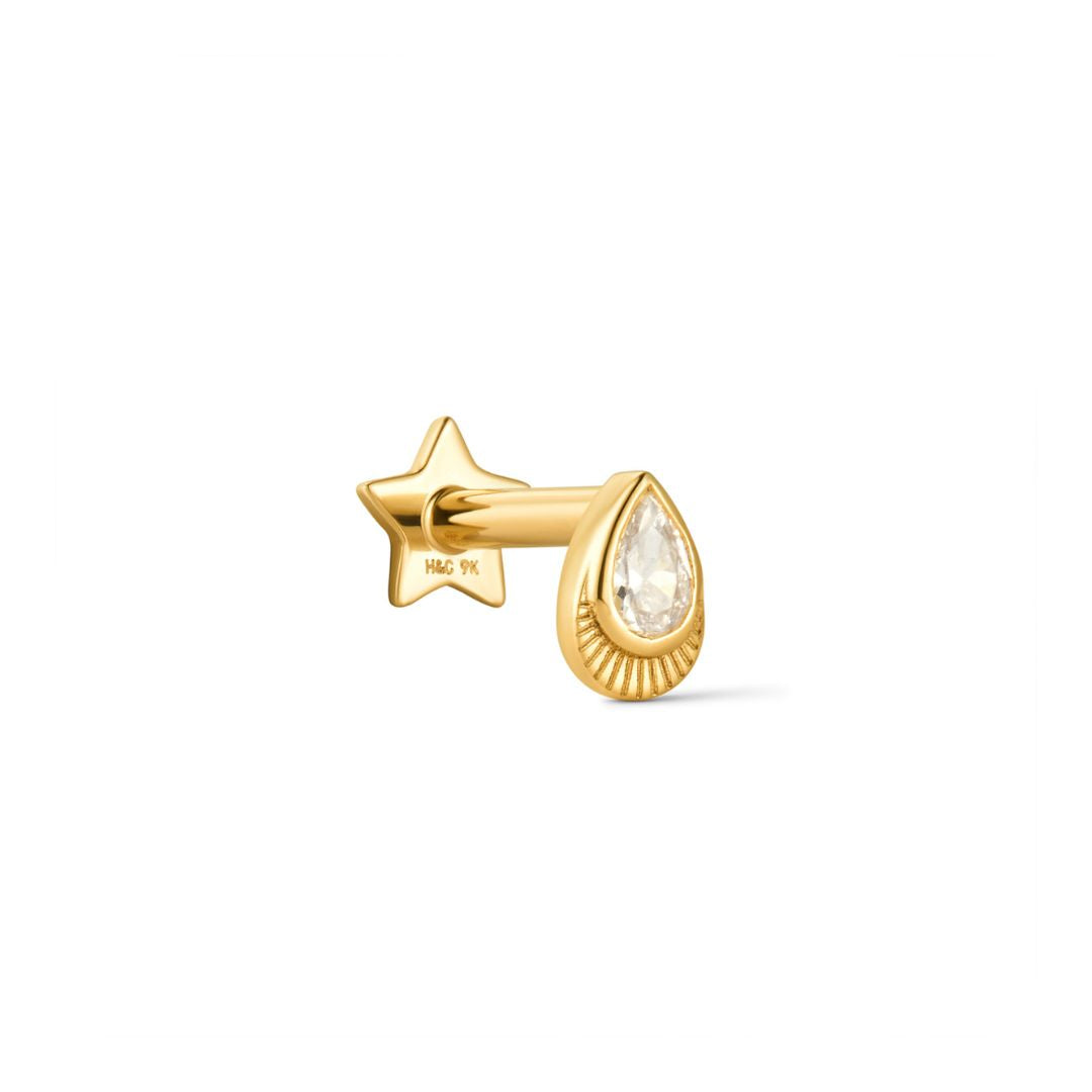 A pear shaped yellow gold stud earring with a bezel set crystal and milgrain detail, part of the Verso Collection.