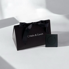 Black gift bag with a bow and 'Helix & Conch' branding on a white background