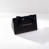 A black gift bag with 'helix & conch' branding, tied with a satin ribbon.