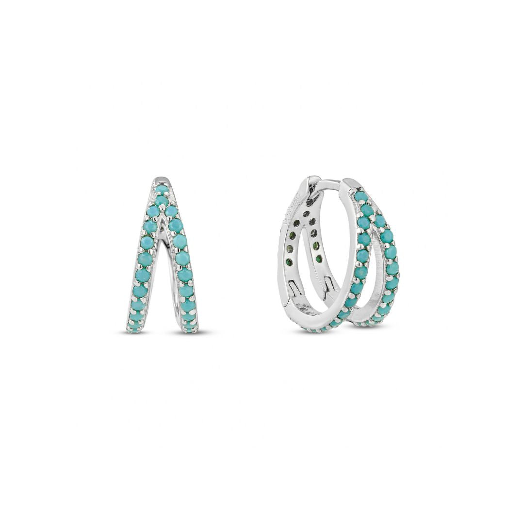 A double hoop earring with turquoise stones on a white gold plated surface, designed to give the illusion of two separate piercings.