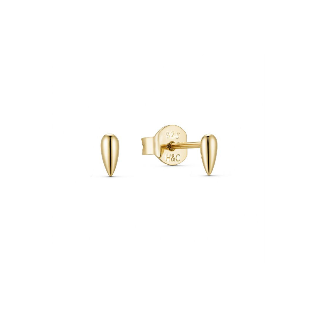 A pair of small, gold plated, seed-shaped stud earrings on a white background.