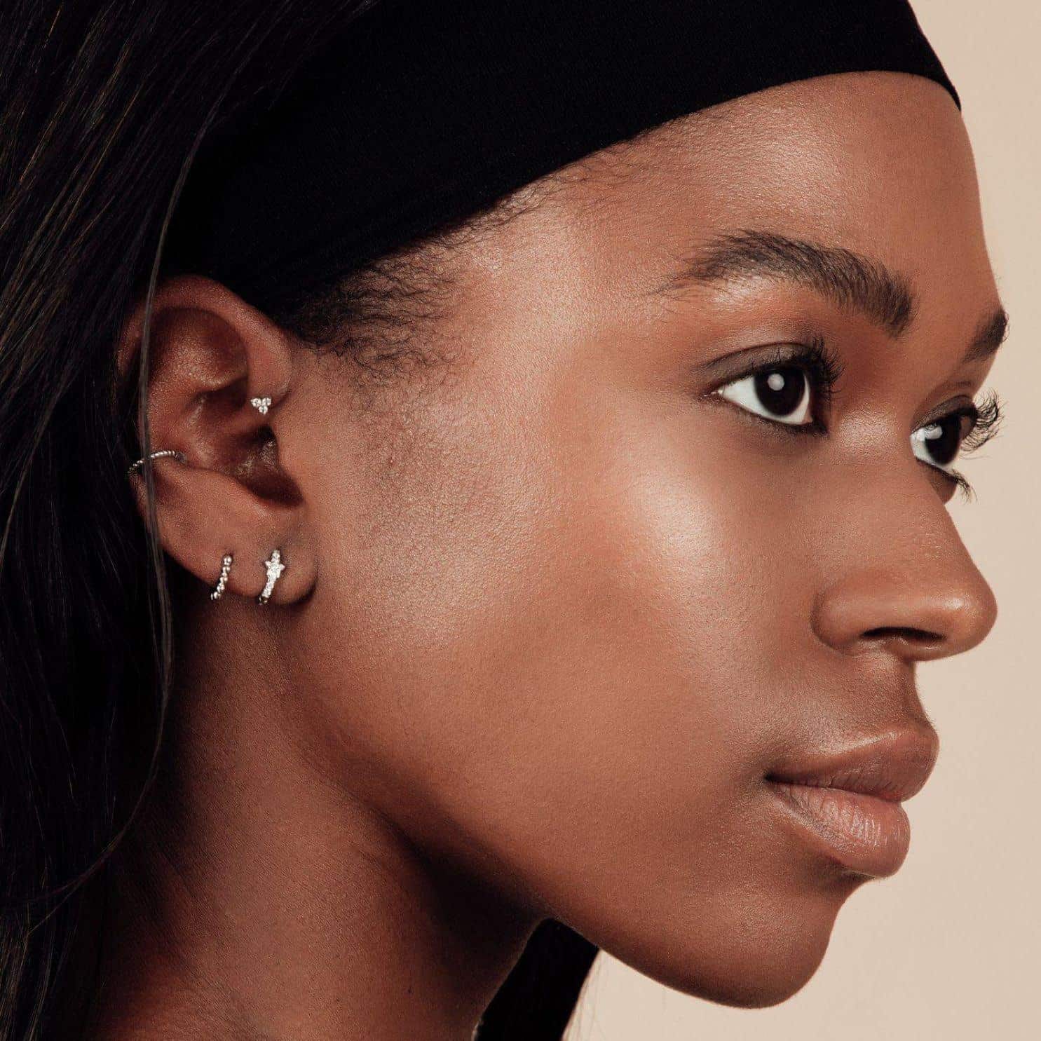 silver huggie hoop earrings on a black womans ear