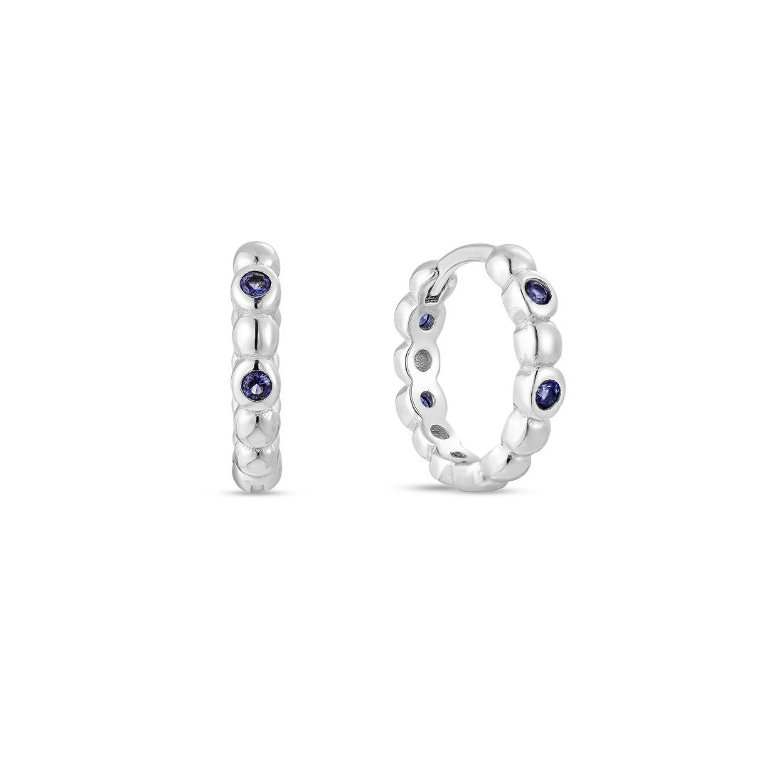 A single white gold plated hoop earring with deep blue sapphire cubic zirconia placed between white gold beading.