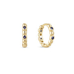 A single yellow gold plated hoop earring with deep sapphire cubic zirconia placed between gold beading.