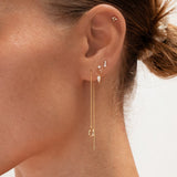 Close-up of an ear with gold earrings and a blurred background