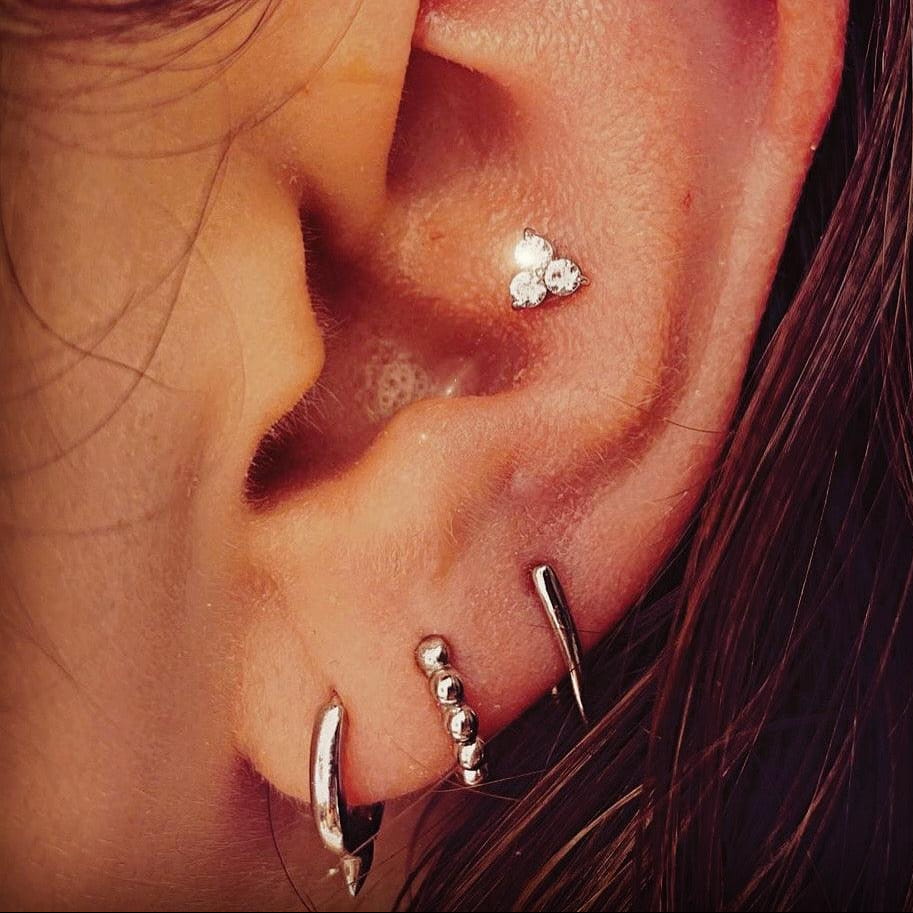 Close-up of an ear with multiple silver earrings