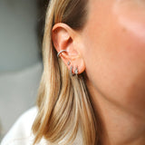Close-up of an ear wearing multiple silver hoop earrings 