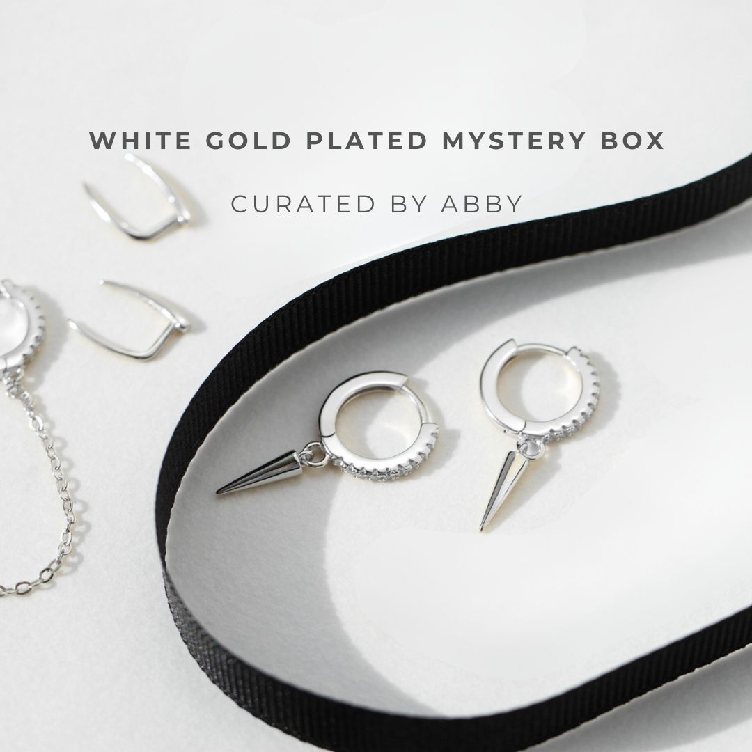 White gold plated jewelry set with a black ribbon on a white background, curated by Abby.