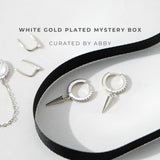 White gold plated jewelry set with a black ribbon on a white background, curated by Abby.